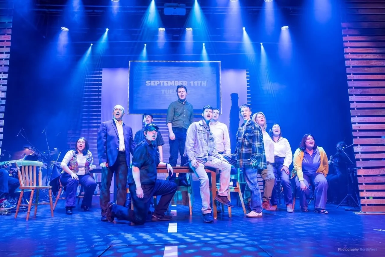 Ensemble performing Come From Away under blue stage lighting