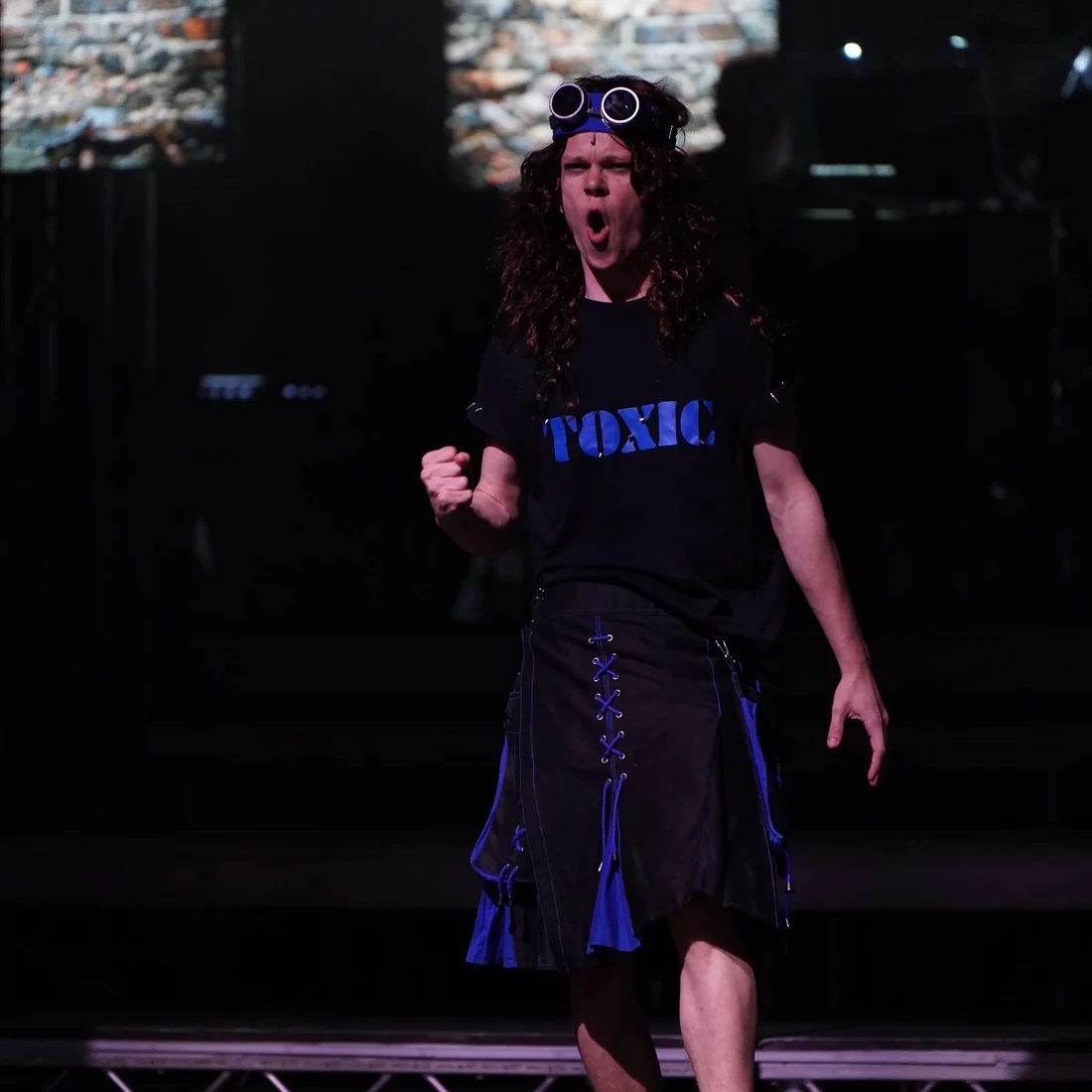 Harry in costume performing We Will Rock You